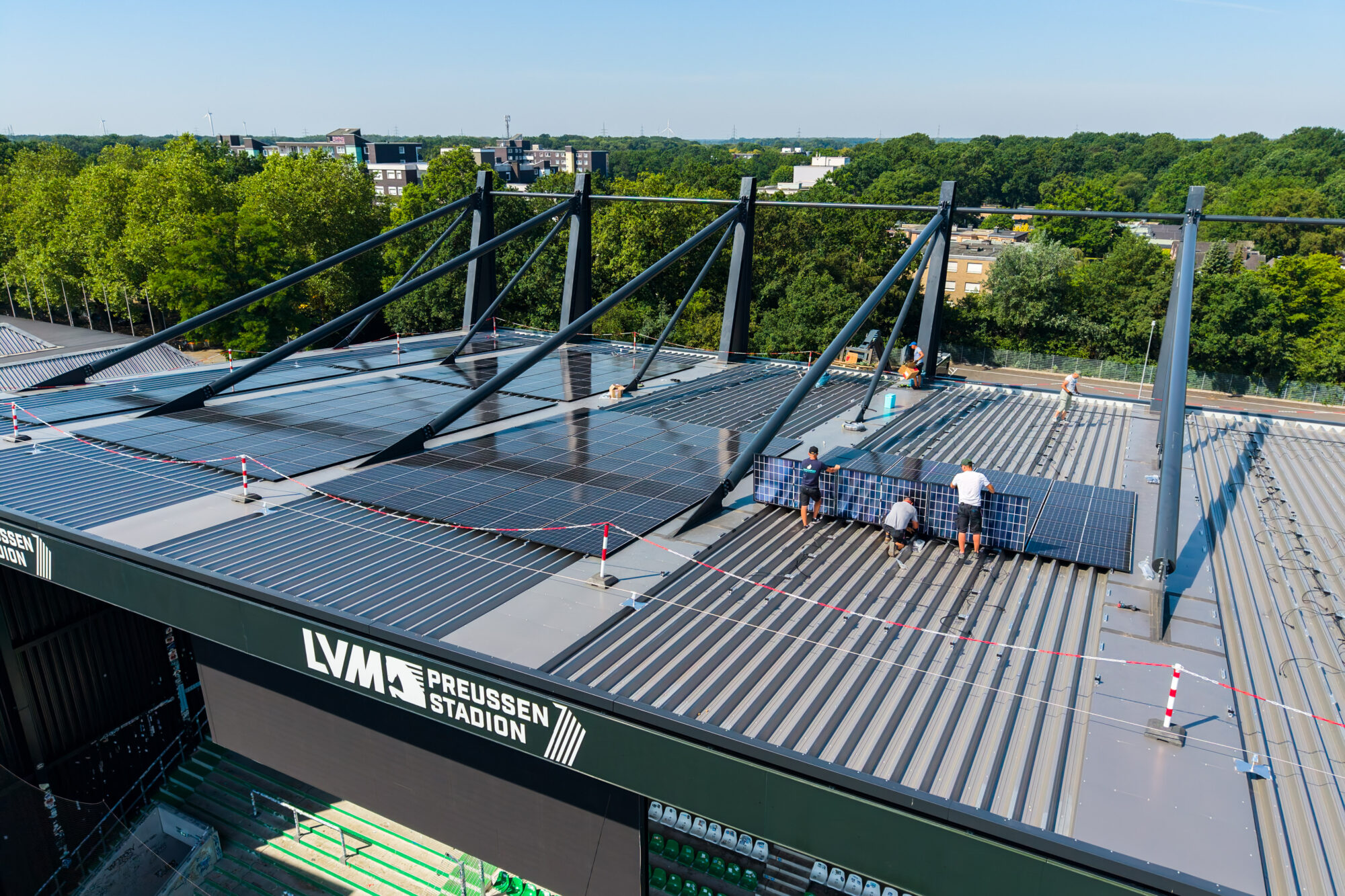 Auf dem Dach der Westtribüne werden die ersten Photovoltaik-Anlagen des LVM-Preußenstadions montiert. Stadt Münster/ Michael Lyra